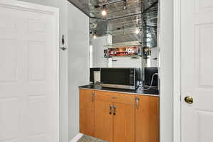 Bar area featuring brown cabinets, an ornate ceiling, and stainless steel microwave