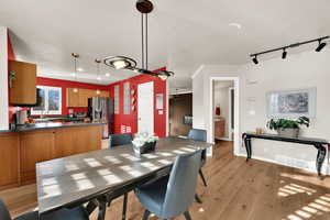 Dining room featuring light wood-type flooring, rail lighting, and a textured ceiling