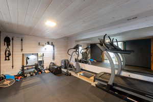 Exercise area featuring wood ceiling, rubber floors, and wood walls
