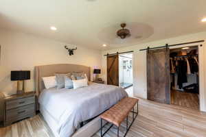 Bedroom featuring wood tiled floors, ceiling fan, a walk in closet, recessed lighting, and ensuite bath