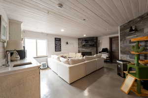 Living area with a fireplace, wooden walls, finished concrete floors, and wooden ceiling