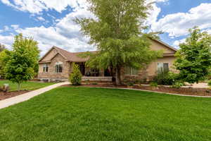 View of front of property featuring stone siding, a front lawn, a porch, and stucco siding
