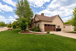 View of property exterior featuring stucco siding, a lawn, stone siding, and concrete driveway