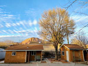 Rear view of property featuring stucco siding, a mountain view, an outbuilding, and a patio area