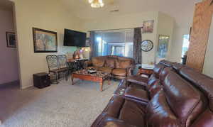 Carpeted living area featuring vaulted ceiling and a ceiling fan