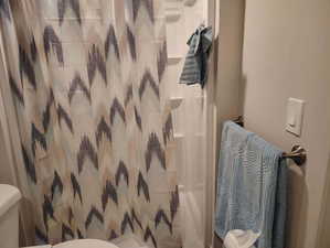 Bathroom with a shower with curtain and toilet