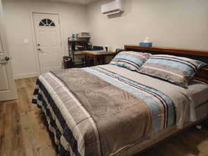 Bedroom with light wood-style floors and a wall mounted air conditioner