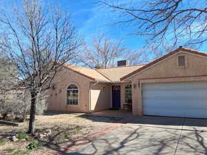 View of front of home with a tiled roof, concrete driveway, stucco siding, an attached garage, and a chimney