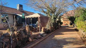 View of property exterior with a chimney, a gazebo, and a tile roof