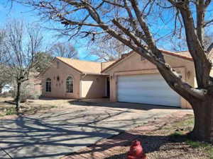 View of front of home with stucco siding, a garage, concrete driveway, and a tile roof