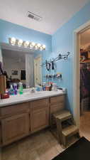 Full bath with a walk in closet, vanity, ceiling fan, a textured ceiling, and a shower with curtain
