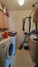 Laundry room with cabinet space, light floors, a textured ceiling, and washer and clothes dryer