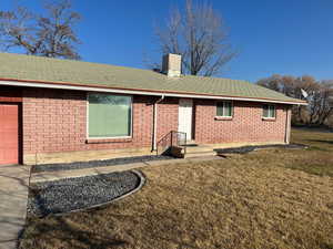 View of front facade with a front yard, a shingled roof, a garage, and brick siding