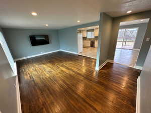 Unfurnished living room featuring dark wood-style floors and recessed lighting
