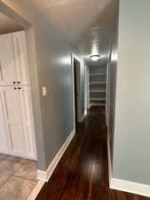 Corridor featuring dark wood finished floors and a textured ceiling