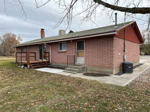 Back of property with a chimney, a lawn, a shingled roof, and brick siding