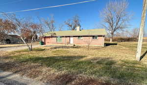 View of front of property featuring brick siding, a chimney, and driveway