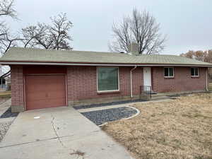 Single story home with roof with shingles, a front yard, concrete driveway, and brick siding