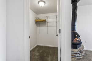 Spacious closet featuring dark carpet and a wood stove