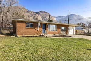 Ranch-style house featuring a mountain view, brick siding, driveway, and a garage