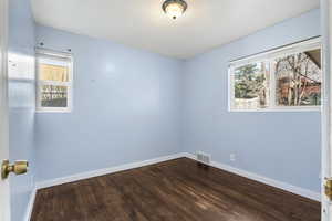 Spare room with dark wood-type flooring and healthy amount of natural light