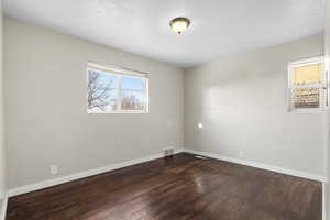 Unfurnished room featuring baseboards and dark wood-style flooring