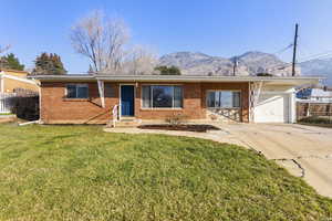 Ranch-style home featuring brick siding, concrete driveway, a mountain view, and a garage