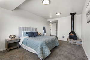 Bedroom with dark carpet and a wood stove