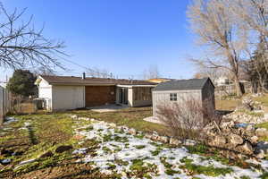 Rear view of house with a storage shed, a patio area, and brick siding