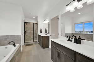 Primary Full bathroom featuring two vanities, a garden tub, a shower stall, and light tile patterned floors