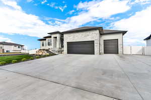 Prairie-style house featuring a garage, stone siding, and driveway