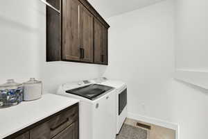 Laundry area with separate washer and dryer, cabinet space, and light wood-type flooring