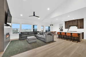 Living area/kitchen with recessed lighting, a tiled fireplace, light wood finished floors, a chandelier, and a ceiling fan