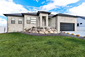 Prairie-style house with stone siding and concrete driveway