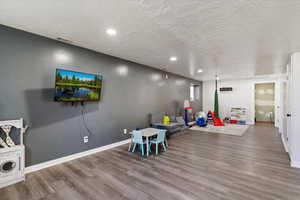 Recreation room with recessed lighting, wood finished floors, and a textured ceiling
