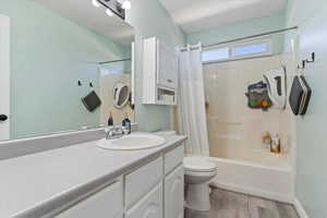 Full bath featuring vanity, shower / bathtub combination with curtain, and light wood-type flooring