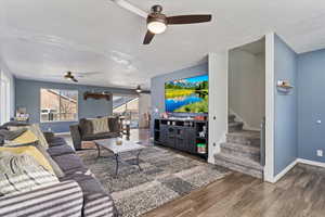 Living room featuring stairs, dark wood finished floors, and ceiling fan