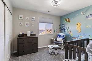 Bedroom featuring a nursery area, a closet, and carpet floors