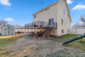 Rear view of property featuring stairs, a deck, a fenced backyard, and a storage shed