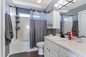 Full bath featuring shower / bath combo with shower curtain, vanity, and dark wood-style flooring
