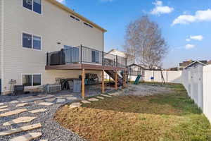 Back of property with a deck, a playground, a fenced backyard, stairs, and a patio