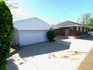Ranch-style house featuring brick siding, a garage, an outbuilding, and driveway