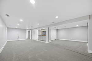 Finished below grade area with light colored carpet and recessed lighting