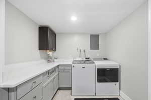 Laundry area featuring electric panel, cabinet space, washer and dryer, and recessed lighting