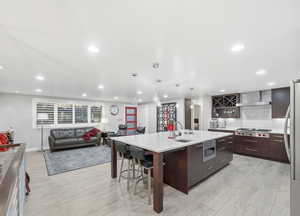 Kitchen with modern cabinets, decorative backsplash, pendant lighting, a center island with sink, and a breakfast bar