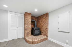 Detailed view of a wood stove, carpet floors, and recessed lighting