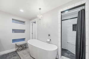Full bathroom with a shower stall, a freestanding bath, a chandelier, wood finished floors, and recessed lighting