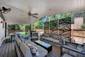 Wooden terrace with a fenced backyard, an outdoor hangout area, ceiling fan, and outdoor dining space