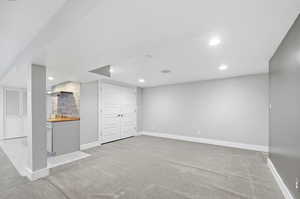 Finished basement with light carpet and recessed lighting