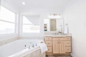 Full bathroom with a jetted tub, vanity, and crown molding
